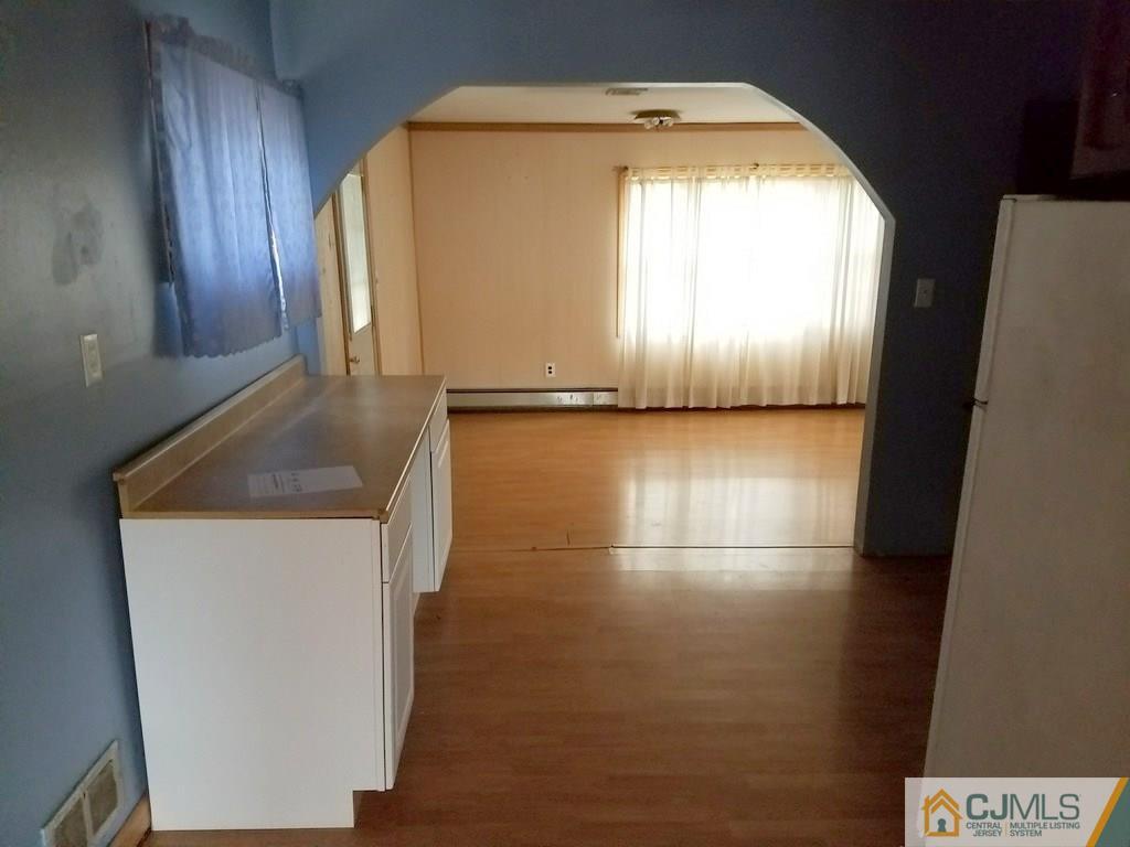 13 Sturgis Road Edison, NJ 08817 - Photo 15 of 22 a view of a refrigerator in kitchen and an empty room with wooden floor