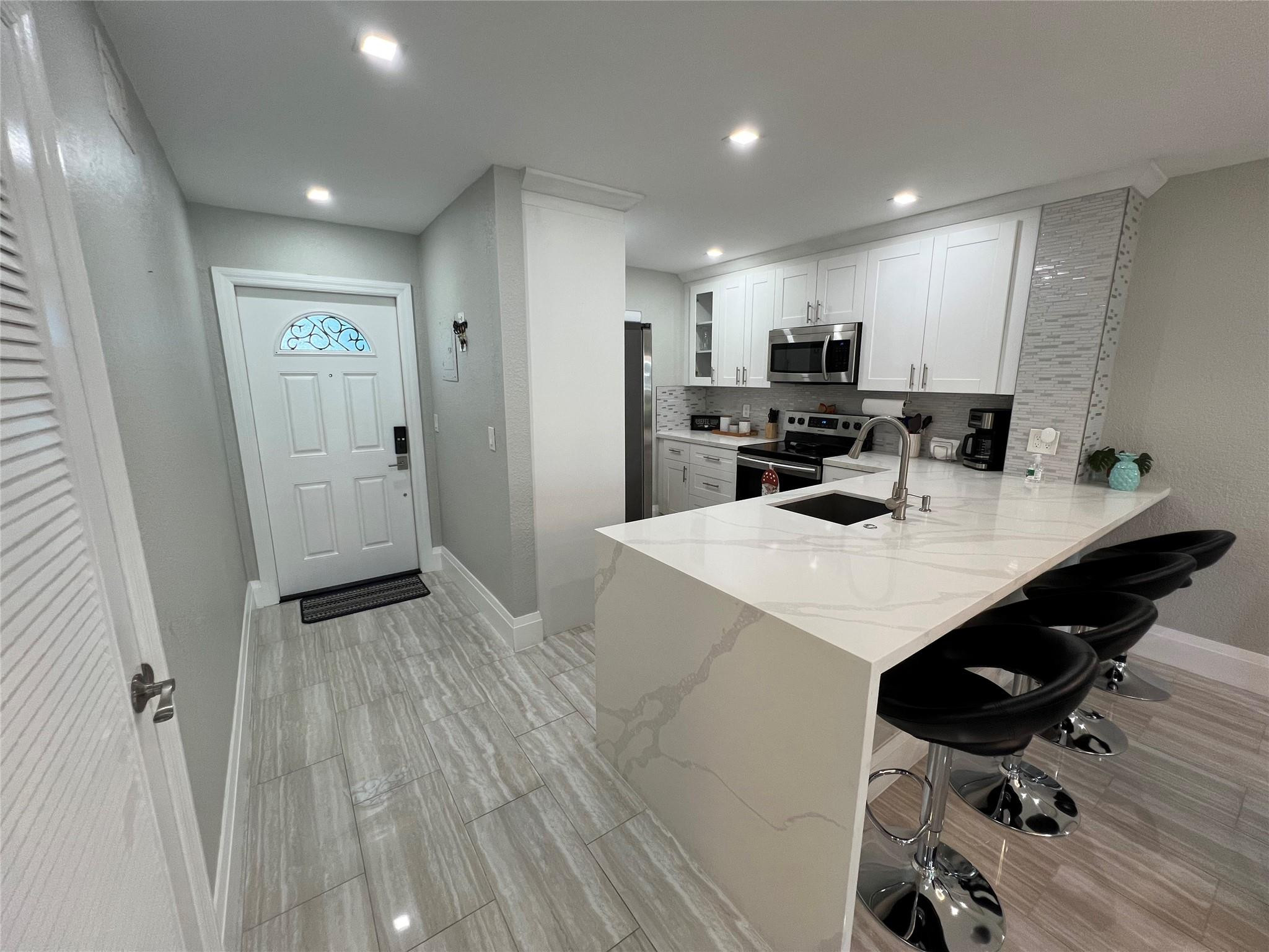 9780 Marina Boulevard, Unit 415 Boca Raton, FL 33428 - Photo 17 of 39 a kitchen with a sink a refrigerator and wooden floor