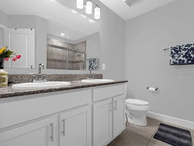 a bathroom with a granite countertop sink and a toilet