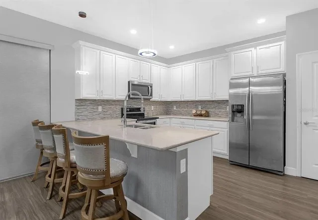 a kitchen with kitchen island granite countertop a sink cabinets and stainless steel appliances