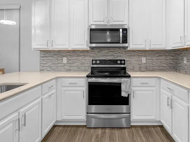 a kitchen with cabinets stainless steel appliances a sink and wooden floor
