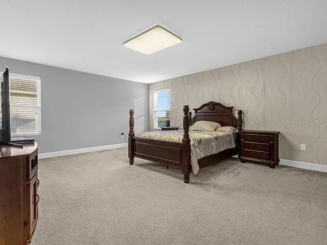 a bedroom with a bed and a flat tv screen on dresser
