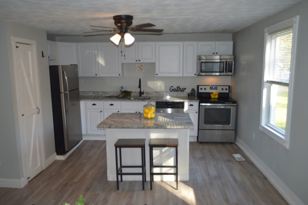 a kitchen with stainless steel appliances a dining table chairs stove refrigerator and microwave