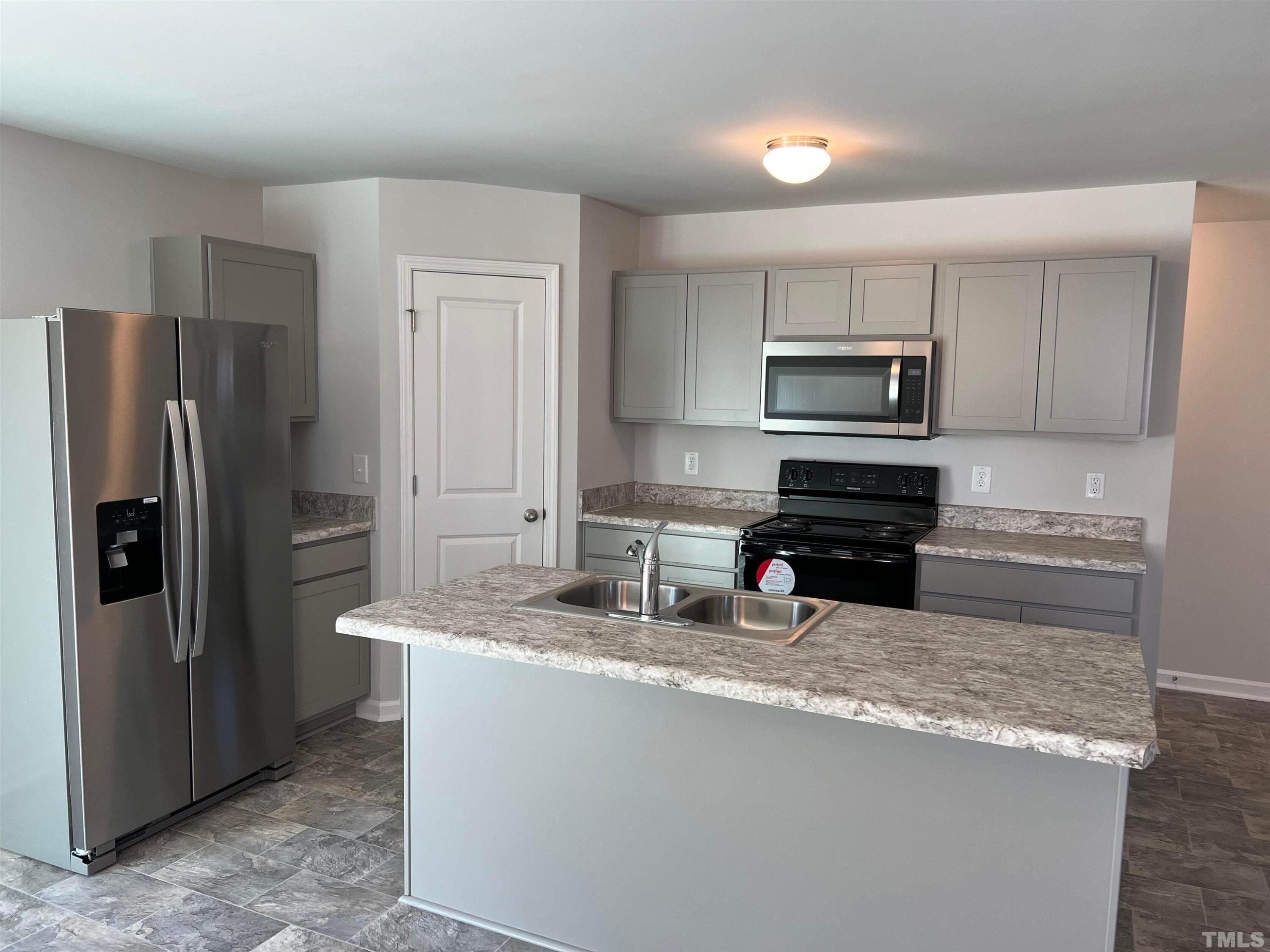 179 Maple Tree Lane Clayton, NC 27527 - Photo 8 of 18 a kitchen with kitchen island granite countertop a refrigerator and a sink