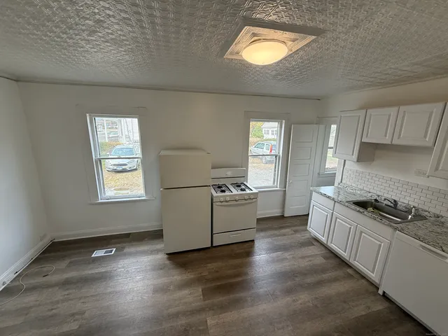 a kitchen with granite countertop a stove a sink and a wooden floors