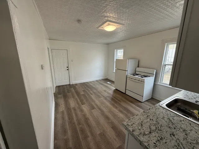 a view of kitchen and empty room with wooden floor