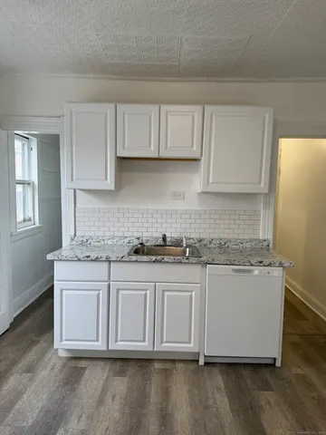 a kitchen with stainless steel appliances granite countertop a stove a sink and a white wooden cabinets