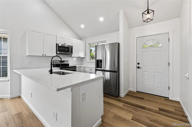 a kitchen with kitchen island a refrigerator sink and wooden floor