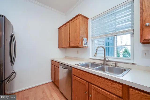 a kitchen with stainless steel appliances granite countertop a sink a refrigerator and wooden cabinets