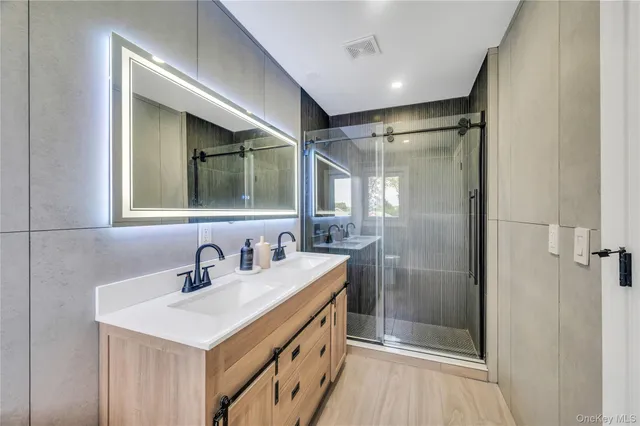 a bathroom with a double vanity sink mirror and shower