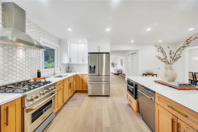 a kitchen with stainless steel appliances a sink dishwasher stove refrigerator and cabinets with wooden floor