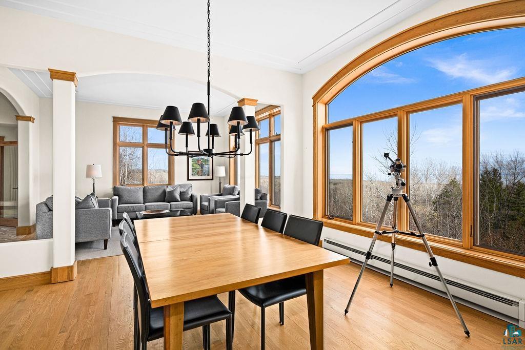 4856 Kingston Street Duluth, MN 55804 - Photo 5 of 88 Open-concept room featuring wood-finish flooring, a contemporary chandelier, arched entryways, and a large arched window framing the outdoor scenery