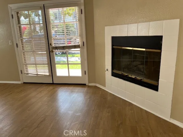 a view of an empty room with wooden floor fireplace and a window