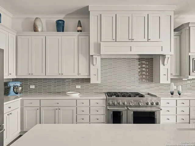 a kitchen with granite countertop white cabinets and stainless steel appliances
