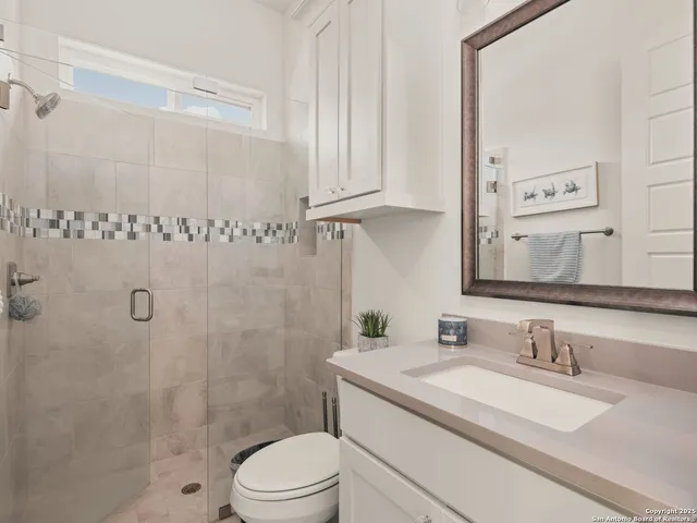 a bathroom with a granite countertop sink a toilet and shower