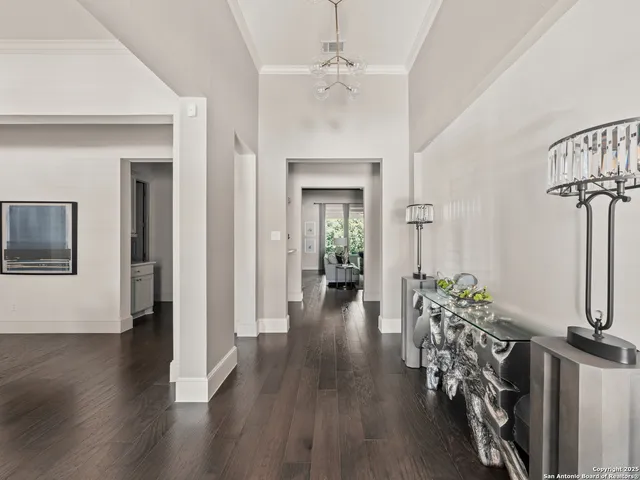 a view of a hallway with wooden floor and a chandelier