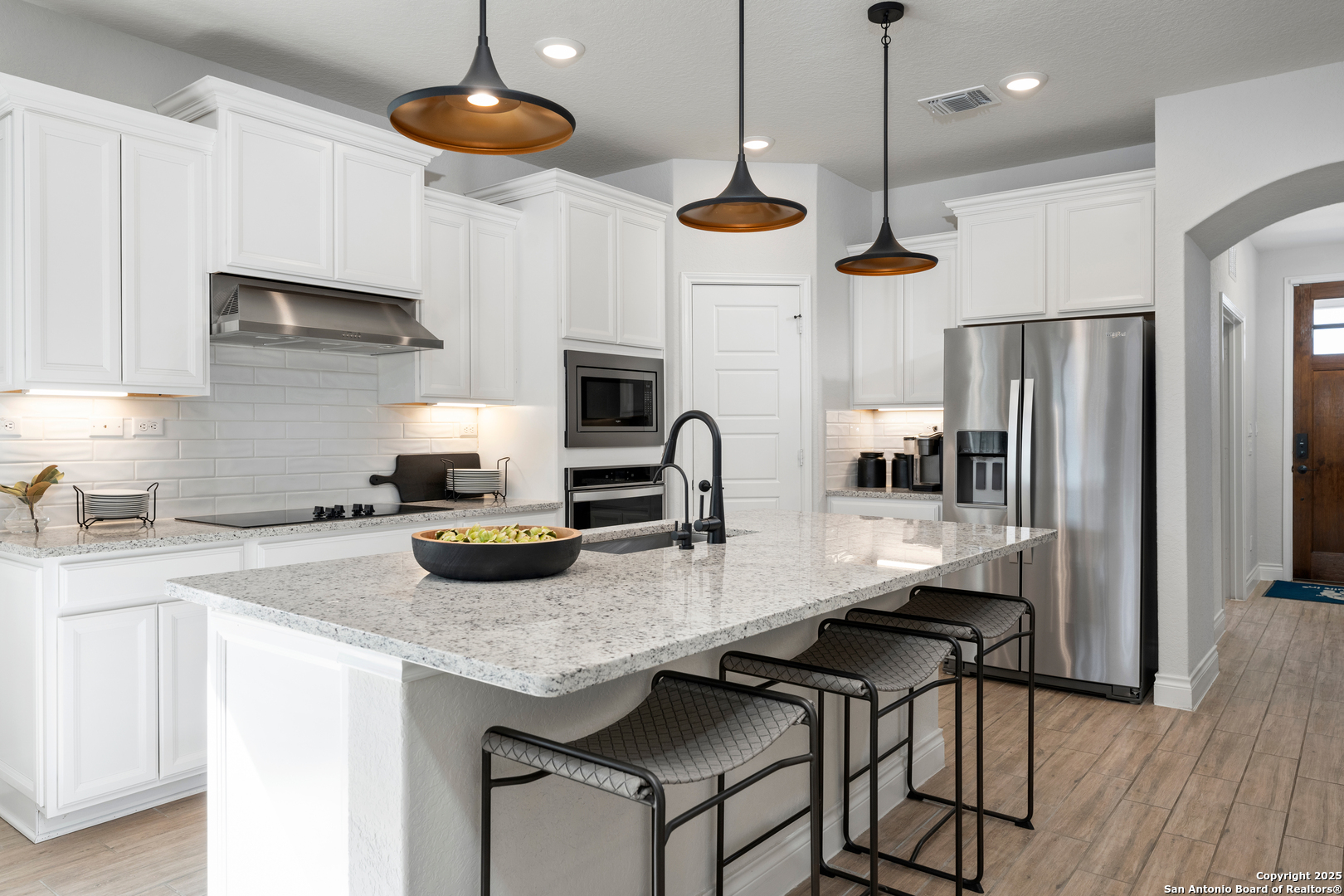 4036 Paddock Trail Seguin, TX 78155 - Photo 7 of 15 a kitchen with stainless steel appliances granite countertop a stove a refrigerator a sink a stove and island with wooden floor