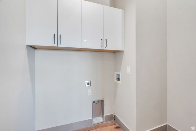 7045 South 300 East Midvale, UT 84047 - Photo 18 of 49 Dedicated utility space featuring overhead white cabinetry with black hardware, wood-finish flooring, and light gray wall paint