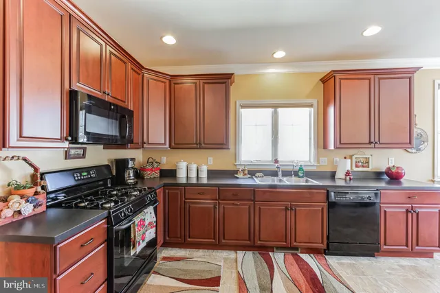 a kitchen with stainless steel appliances granite countertop a stove a sink dishwasher and a microwave oven with wooden cabinets