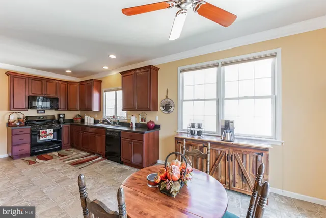 a kitchen with stainless steel appliances kitchen island granite countertop a stove a sink a dining table and chairs with wooden floor