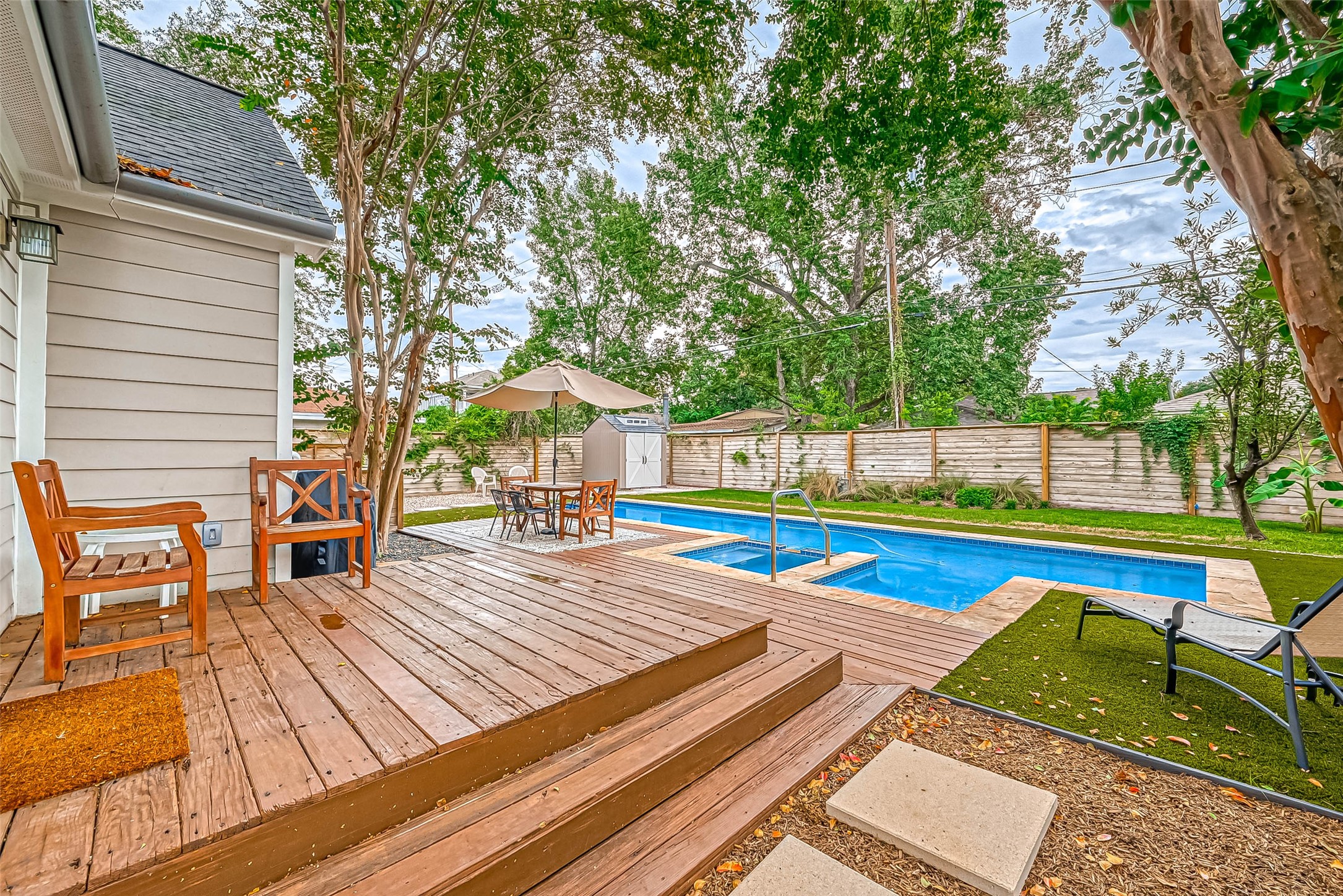 412 Sue Street Houston, TX 77009 - Photo 16 of 19 Charming backyard with a wooden deck, comfortable seating, and a refreshing pool, hot tub and fire pit. It's perfect for outdoor entertaining and relaxation, surrounded by lush greenery and a privacy fence.