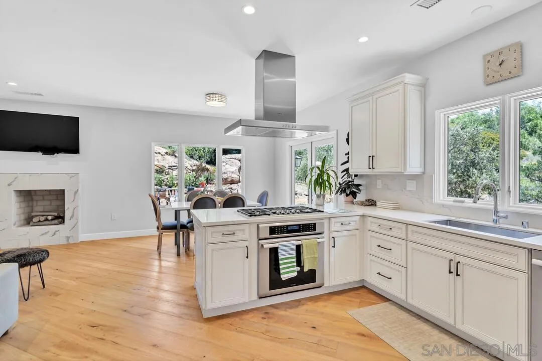 1356 Real Way Lane Alpine, CA 91901 - Photo 14 of 58 a kitchen with stainless steel appliances a stove a sink dishwasher and a fireplace with wooden floor