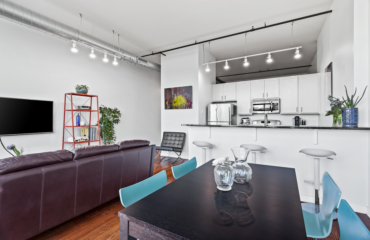 1224 West Van Buren Street, Unit 822 Chicago, IL 60607 - Photo 4 of 21 a kitchen with stainless steel appliances granite countertop a sink dishwasher a dining table and chairs with wooden floor
