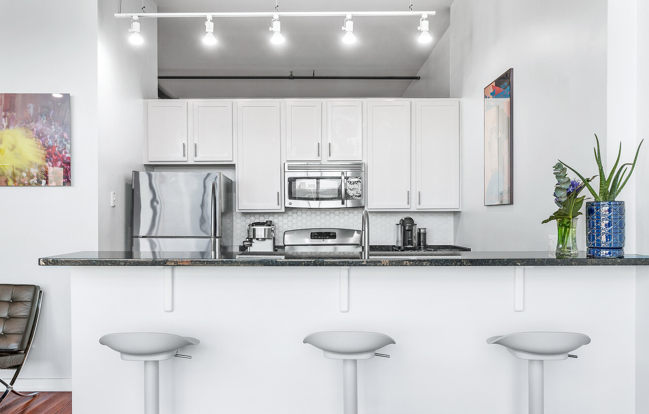 1224 West Van Buren Street, Unit 822 Chicago, IL 60607 - Photo 7 of 21 a kitchen with stainless steel appliances granite countertop a sink and a refrigerator