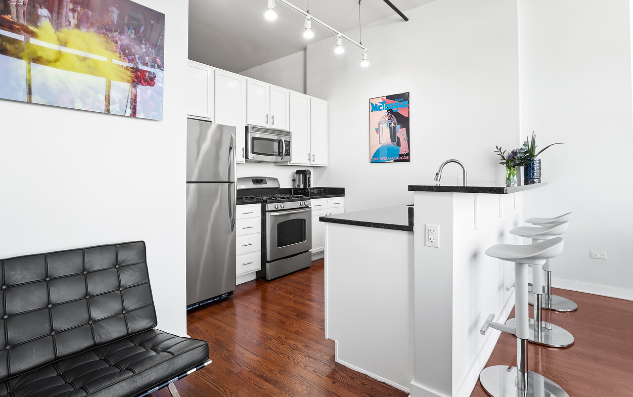 1224 West Van Buren Street, Unit 822 Chicago, IL 60607 - Photo 8 of 21 a kitchen with stainless steel appliances a refrigerator a stove a sink a microwave and wooden floor