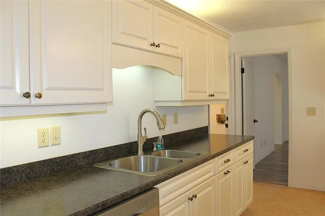 a kitchen with granite countertop a stove and white cabinets