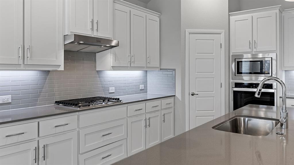 11312 Treehouse Trail Justin, TX 76247 - Photo 4 of 31 a kitchen with white cabinets and a stove