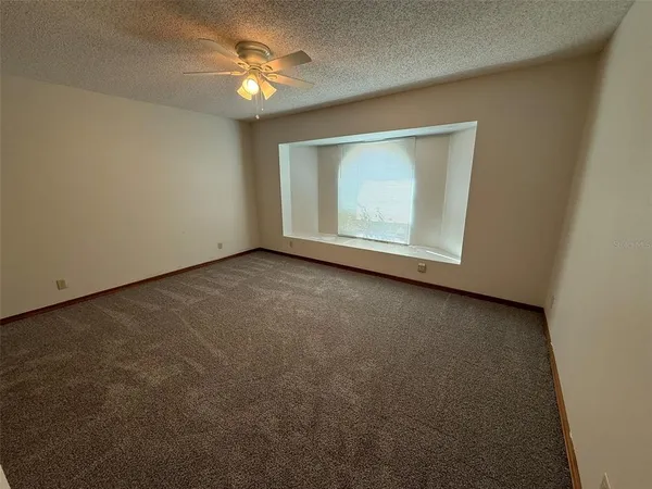 an empty room with a ceiling fan and a window