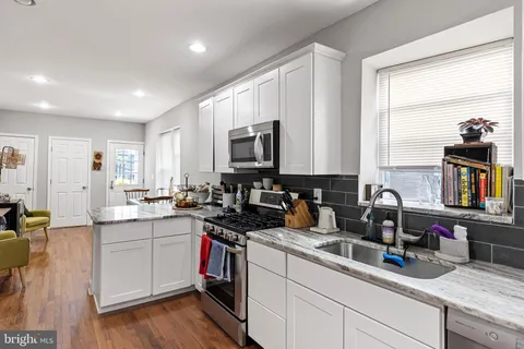 a kitchen with a sink stove cabinets and wooden floor