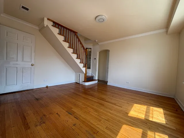 a view of an empty room with wooden floor and stairs