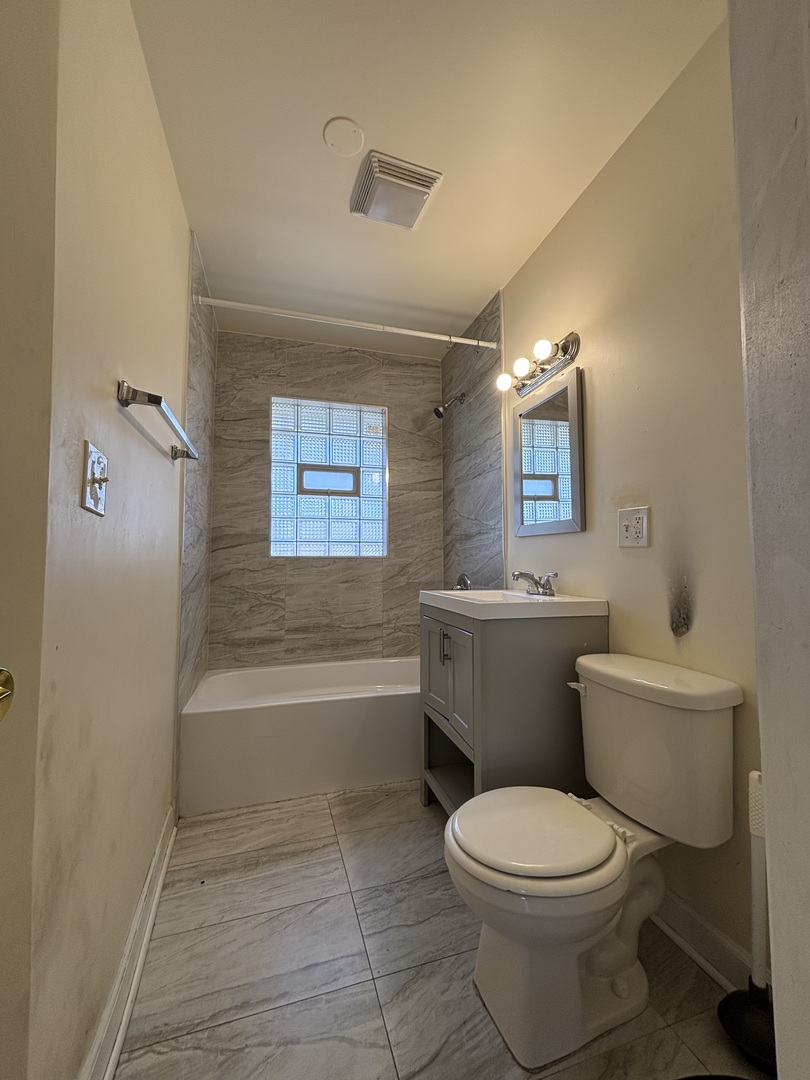 2530 North Neva Avenue Chicago, IL 60707 - Photo 18 of 50 a bathroom with a toilet a sink a mirror and a bathtub
