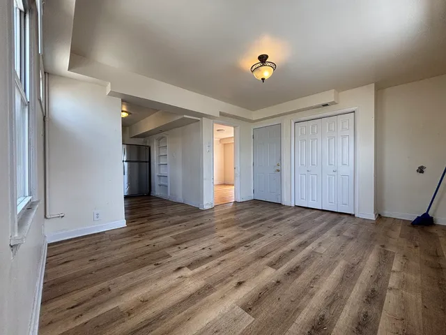 a view of an empty room with wooden floor and a window