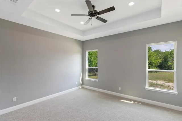an empty room with windows and ceiling fan