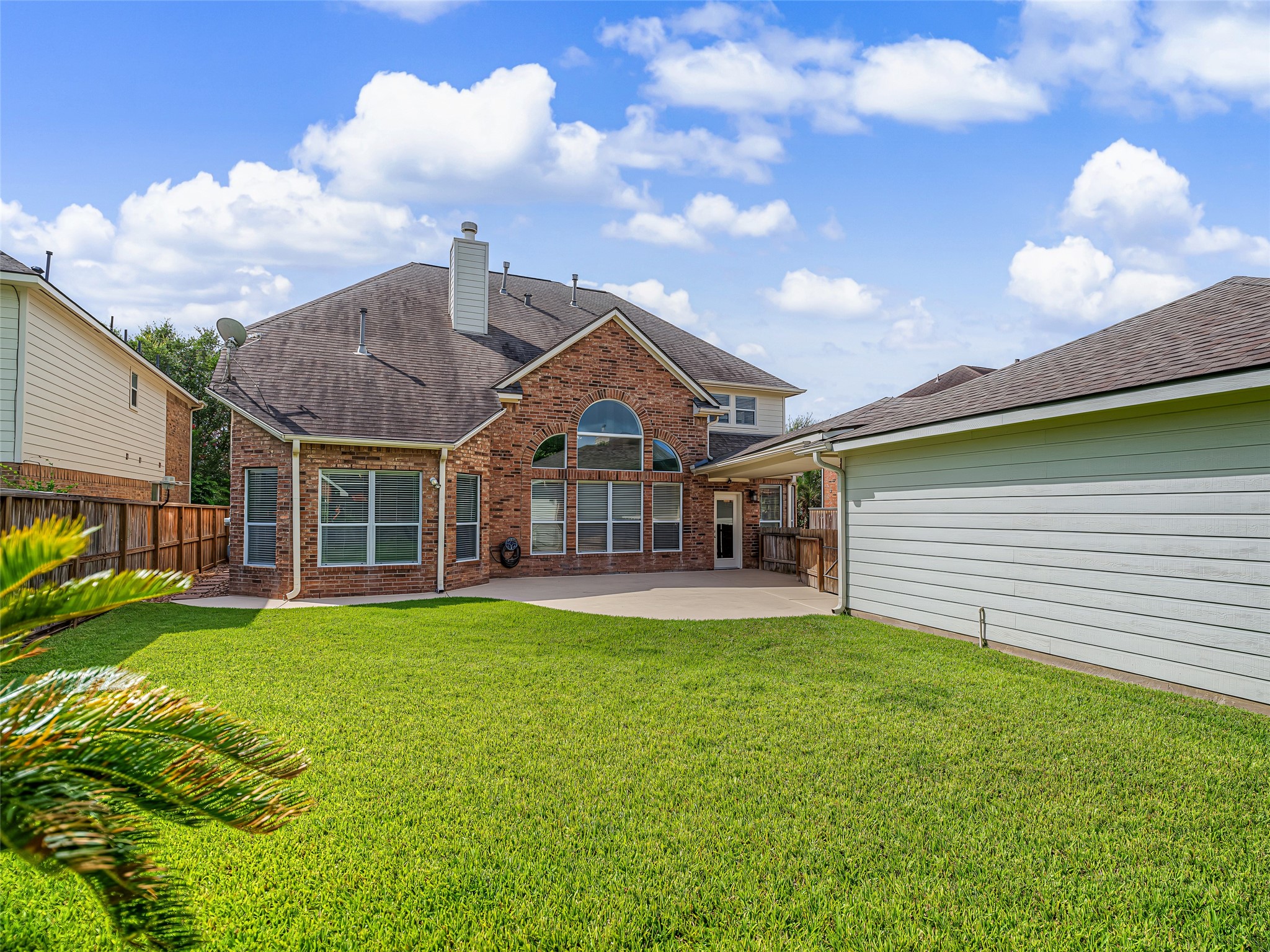 2210 Fox Path Katy, TX 77494 - Photo 43 of 47 From this vantage point, you can fully appreciate the home’s stunning rear architecture. The dramatic, two-story bank of arched windows floods the indoor family room with light while anchoring the home's upscale backyard aesthetic.