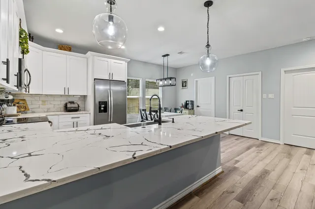 a large kitchen with kitchen island a large counter space a sink appliances and cabinets