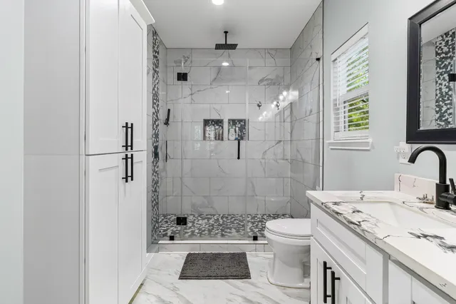 a bathroom with a granite countertop sink a toilet and shower