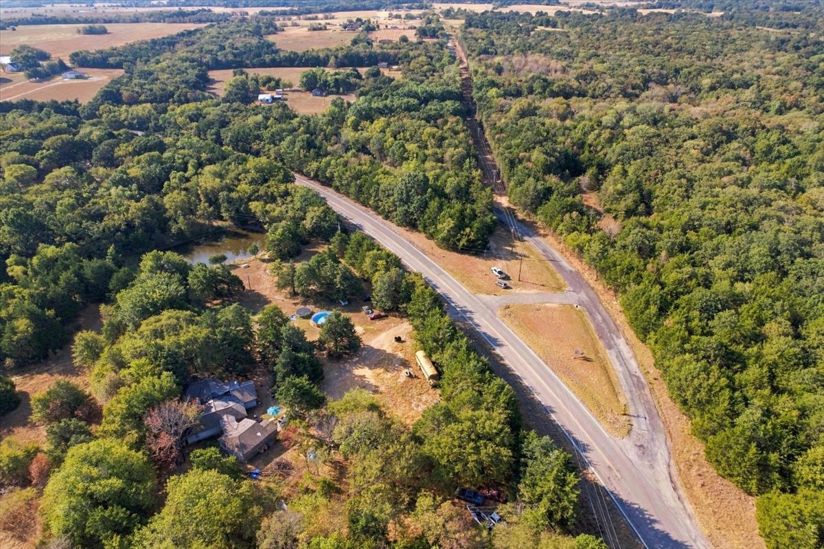 Expansive treed acreage with a private pond, paved road frontage, and a residential structure