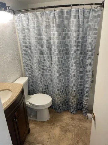 a bathroom with a toilet and a shower curtain