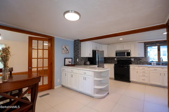 a kitchen with stainless steel appliances granite countertop a refrigerator a stove and white cabinets with wooden floor