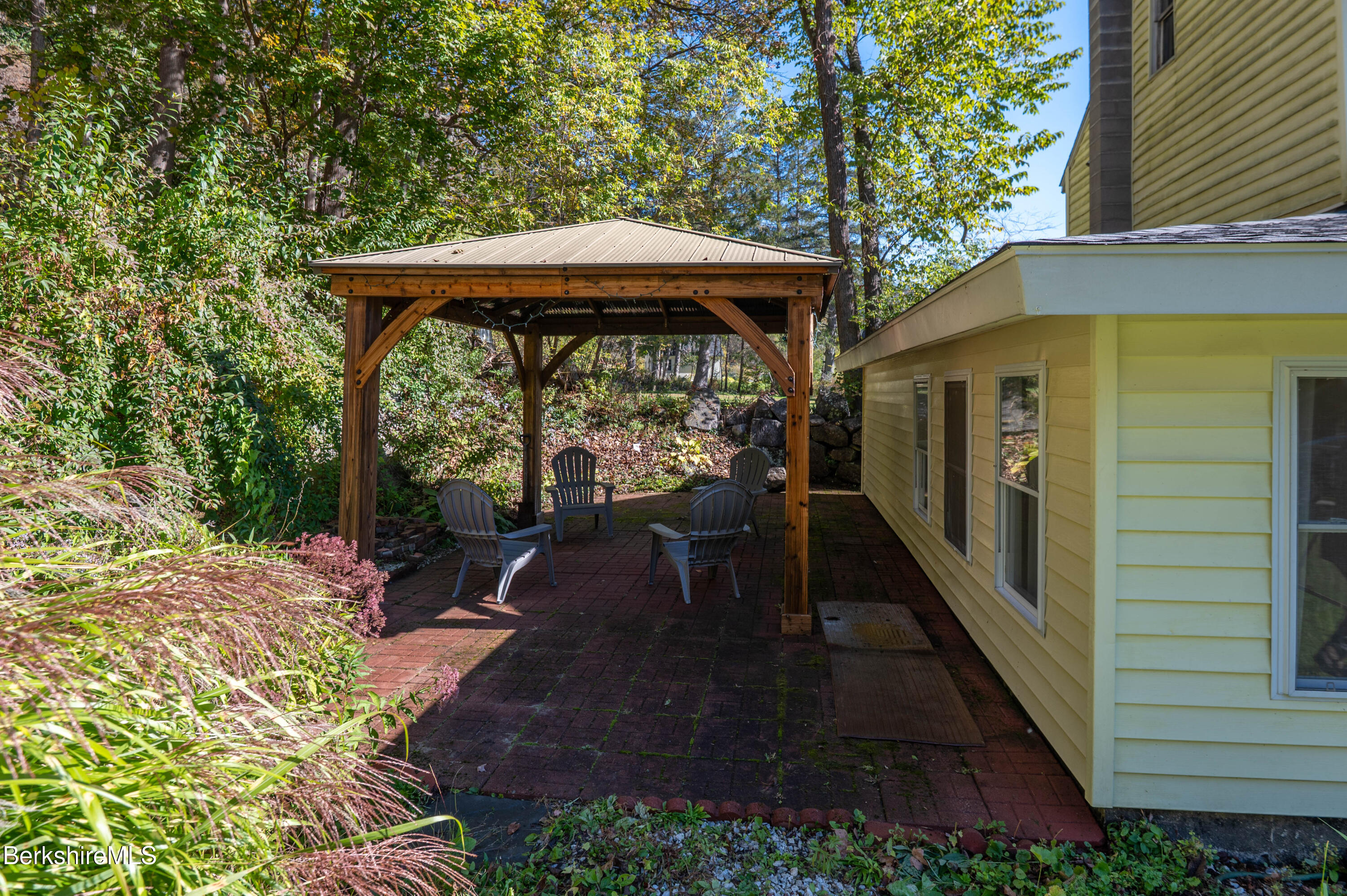 1600 Pleasant Street Lee, MA 01260 - Photo 5 of 26 a view of a patio with table and chairs under an umbrella with large trees