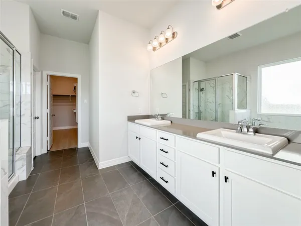 a bathroom with a sink double vanity granite tub and a mirror