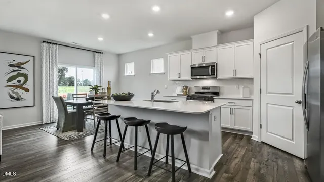 a kitchen with stainless steel appliances granite countertop a stove a sink a microwave a refrigerator and white cabinets with wooden floor