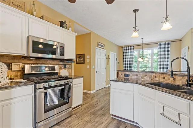 a kitchen with stainless steel appliances granite countertop a stove a sink and a microwave