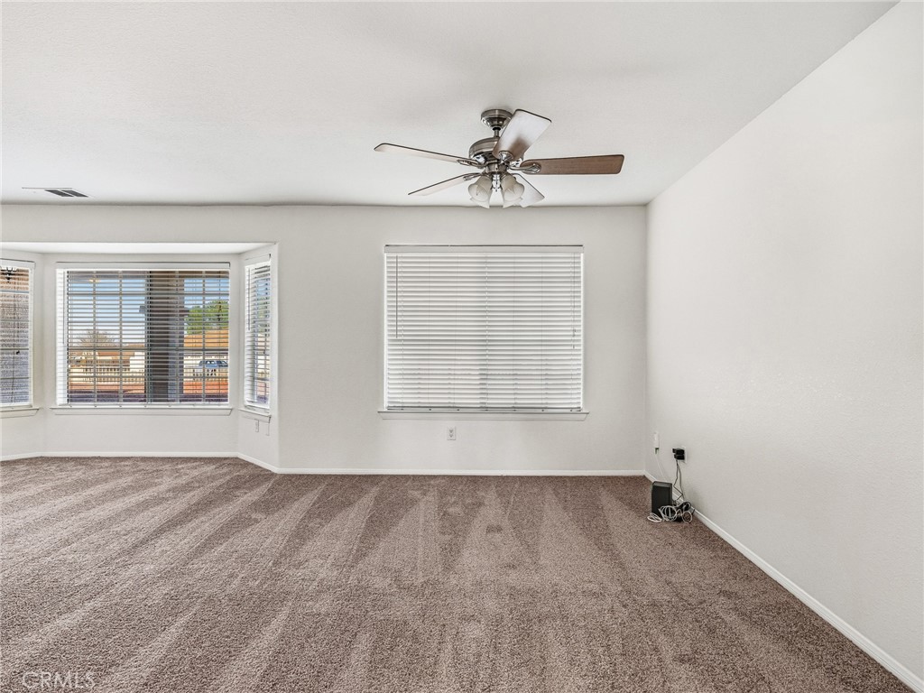 9550 Riggins Road Phelan, CA 92371 - Photo 5 of 47 an empty room with wooden floor chandelier fan and windows