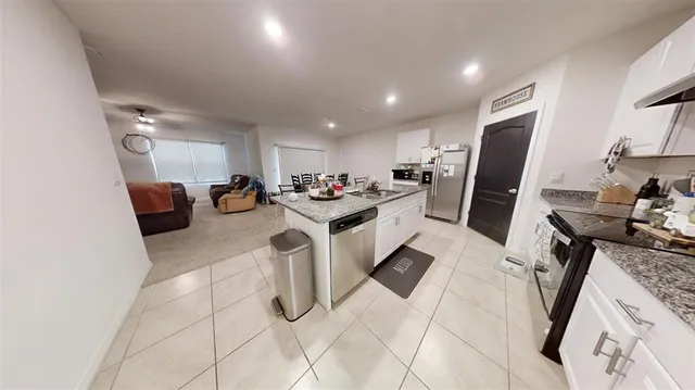 a kitchen with stainless steel appliances kitchen island granite countertop a sink stove and refrigerator