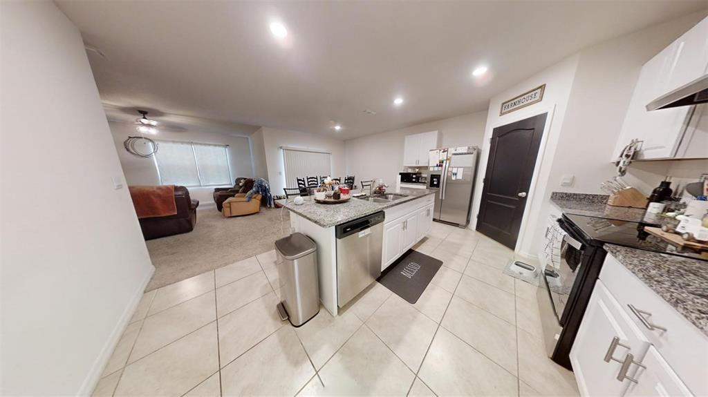 1818 Myrtlebrooke Drive Edgewater, FL 32141 - Photo 14 of 23 a kitchen with stainless steel appliances kitchen island granite countertop a sink stove and refrigerator